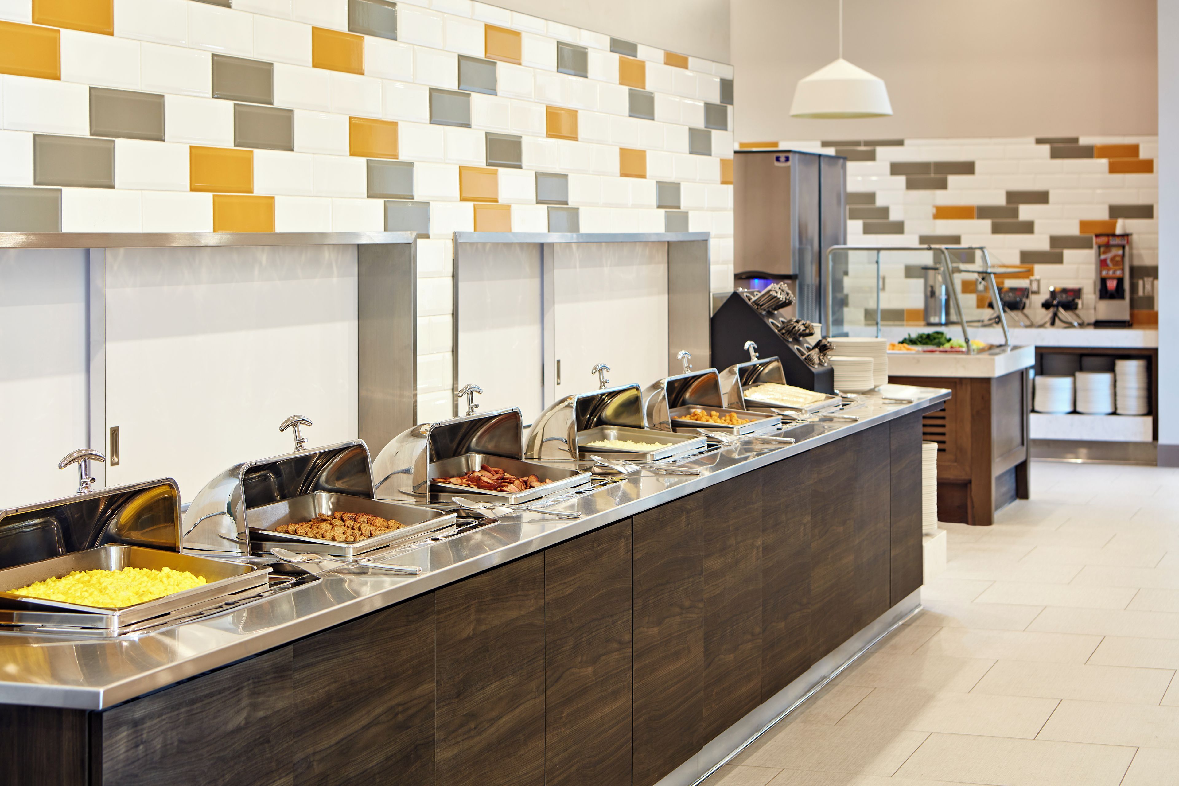 Un'area buffet con diverse postazioni e un moderno rivestimento a piastrelle.