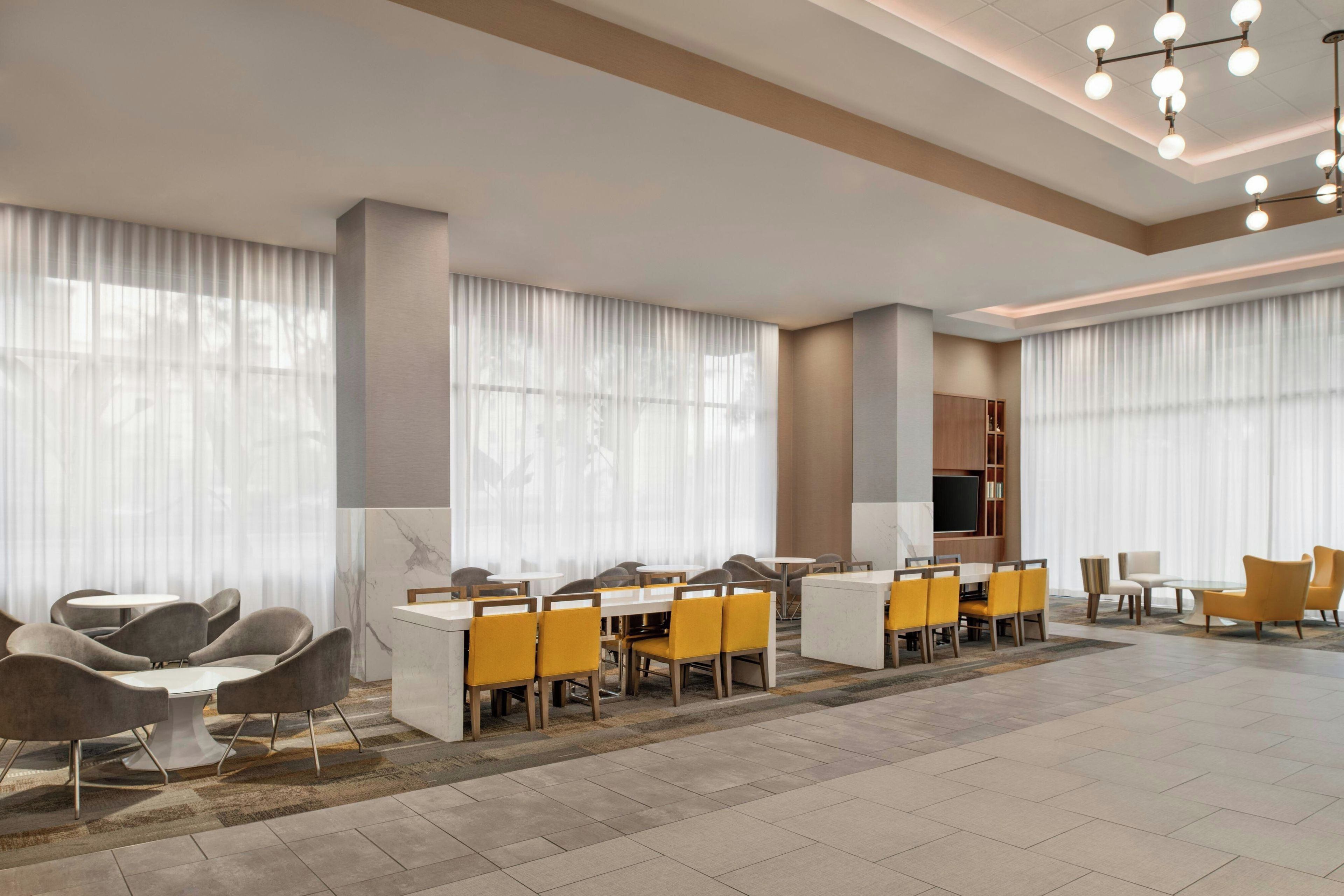 A hotel lobby with a seating area, a television, and a reception desk.
