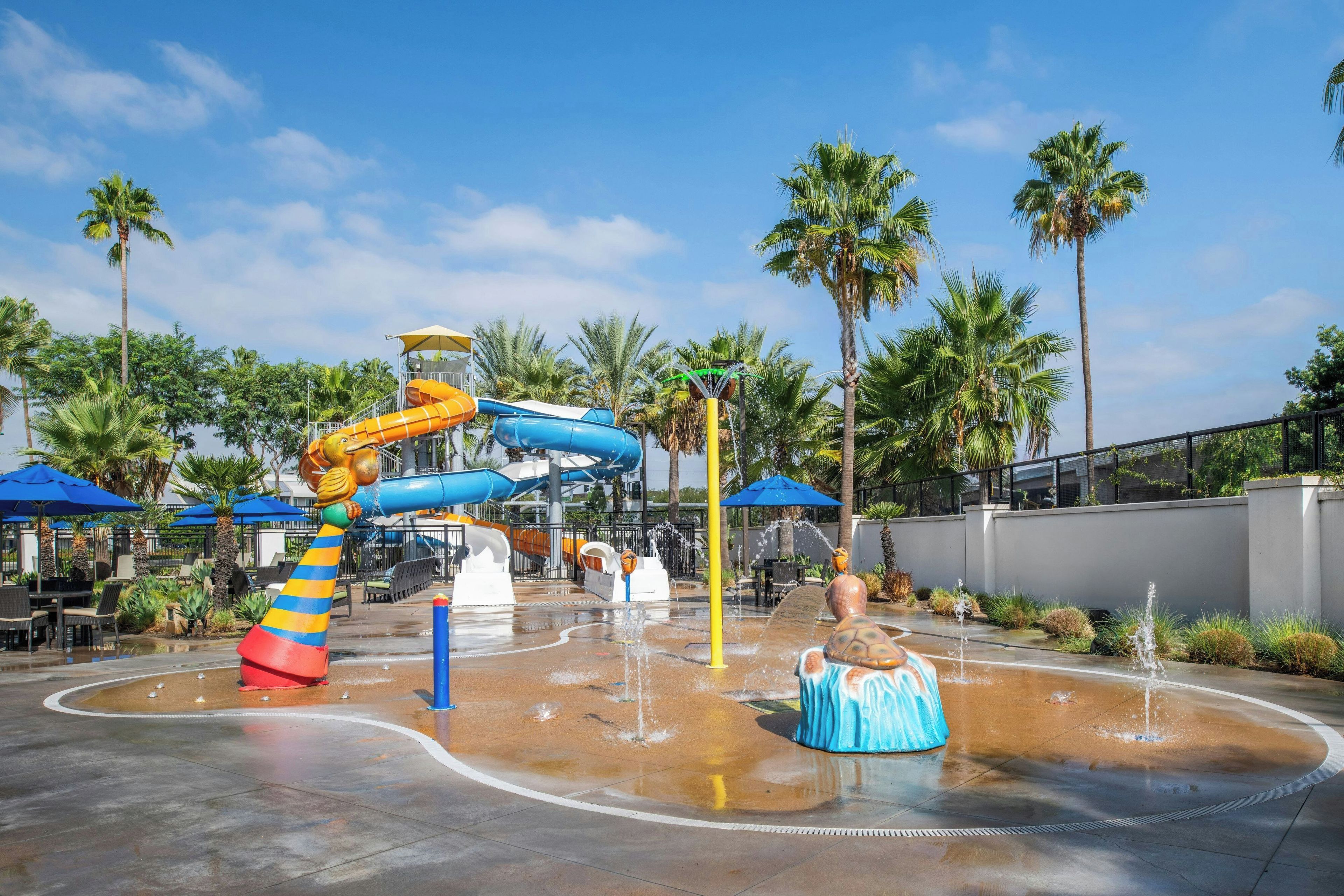 Parque acuático al aire libre con toboganes y fuentes de agua.