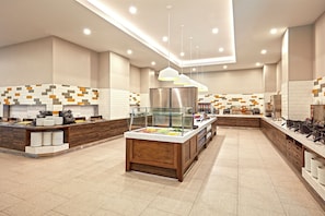 Una presentación de buffet moderna, con una zona central de servicio, varias estaciones de comida y un diseño limpio y contemporáneo.