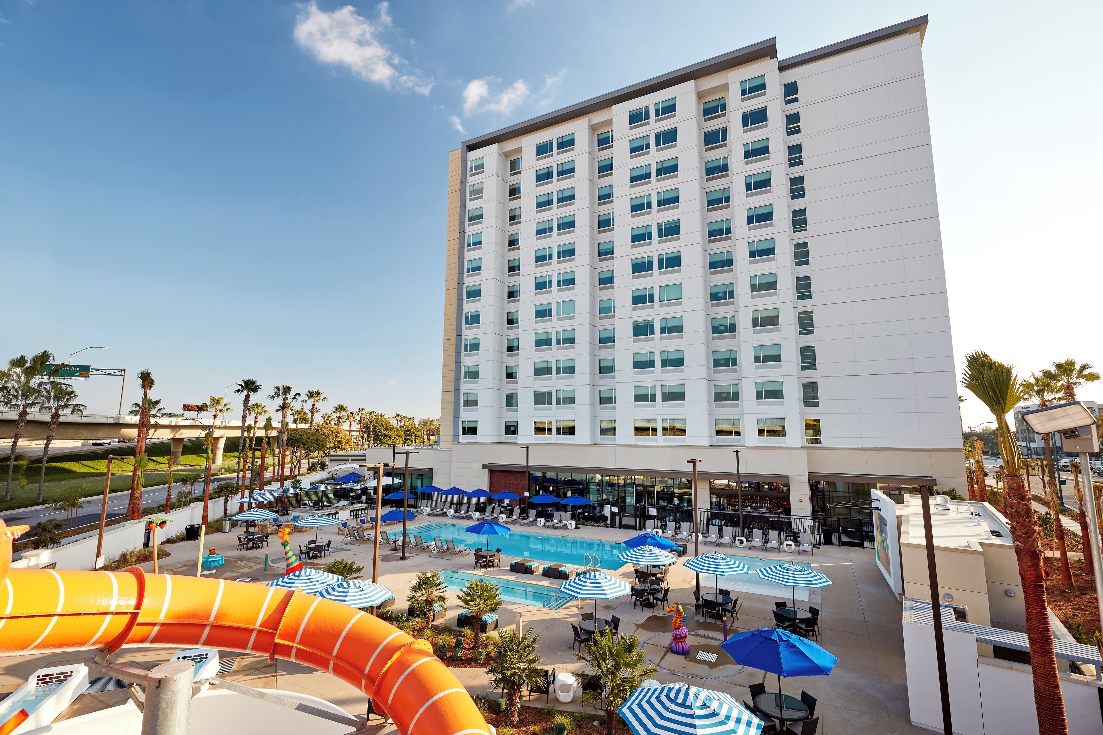 Un hotel con piscina, sillas de descanso y sombrillas.