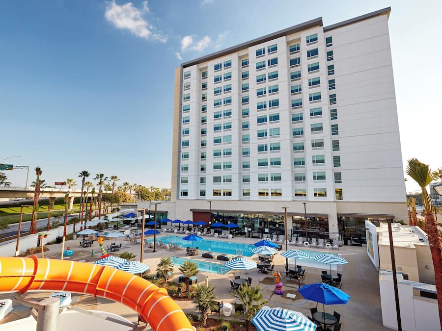 A hotel with a swimming pool, lounge chairs, and umbrellas.
