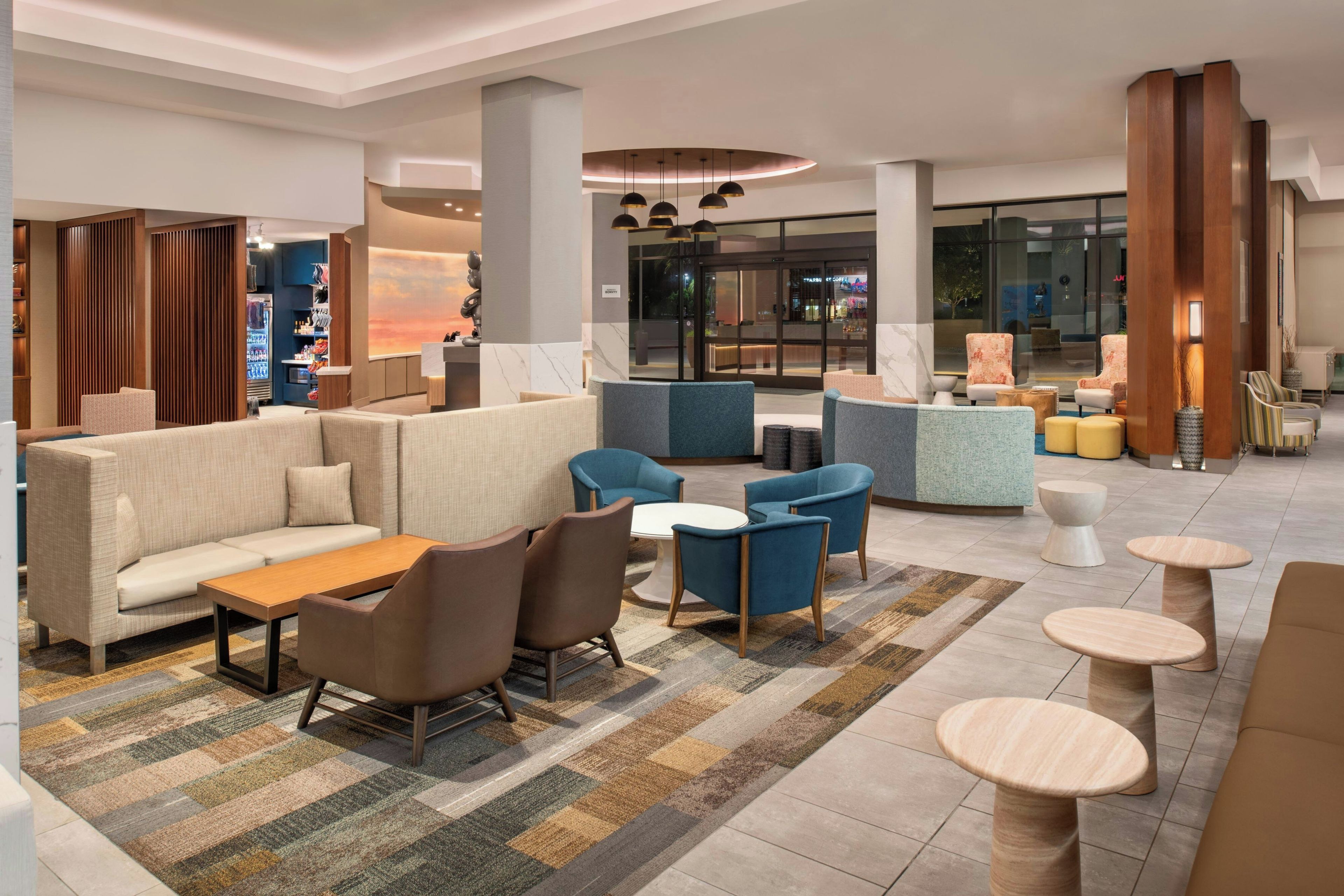 A modern lobby with seating areas, a coffee shop, and a view of the street.