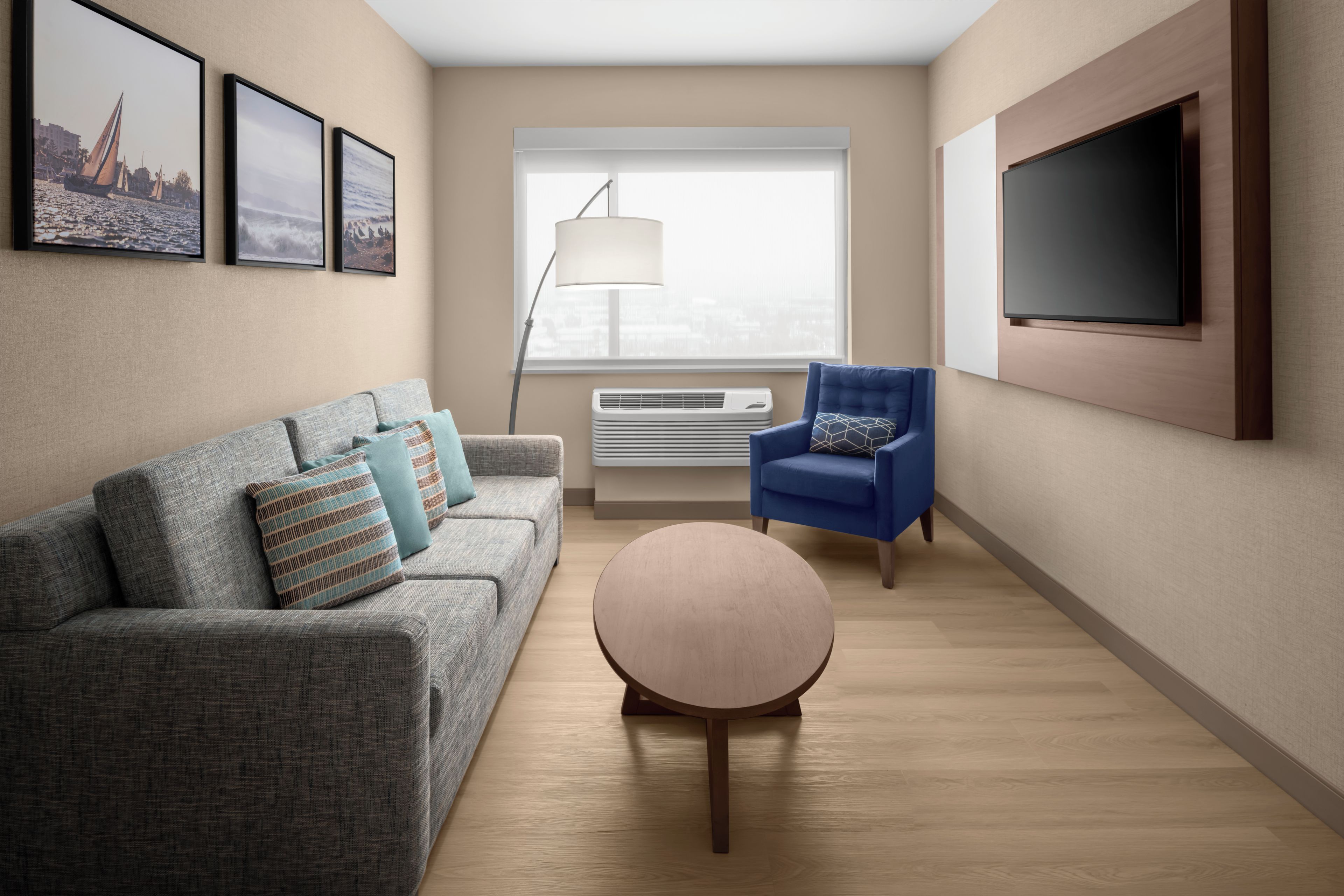 A modern living room with a grey sofa, blue armchair, and a round coffee table.