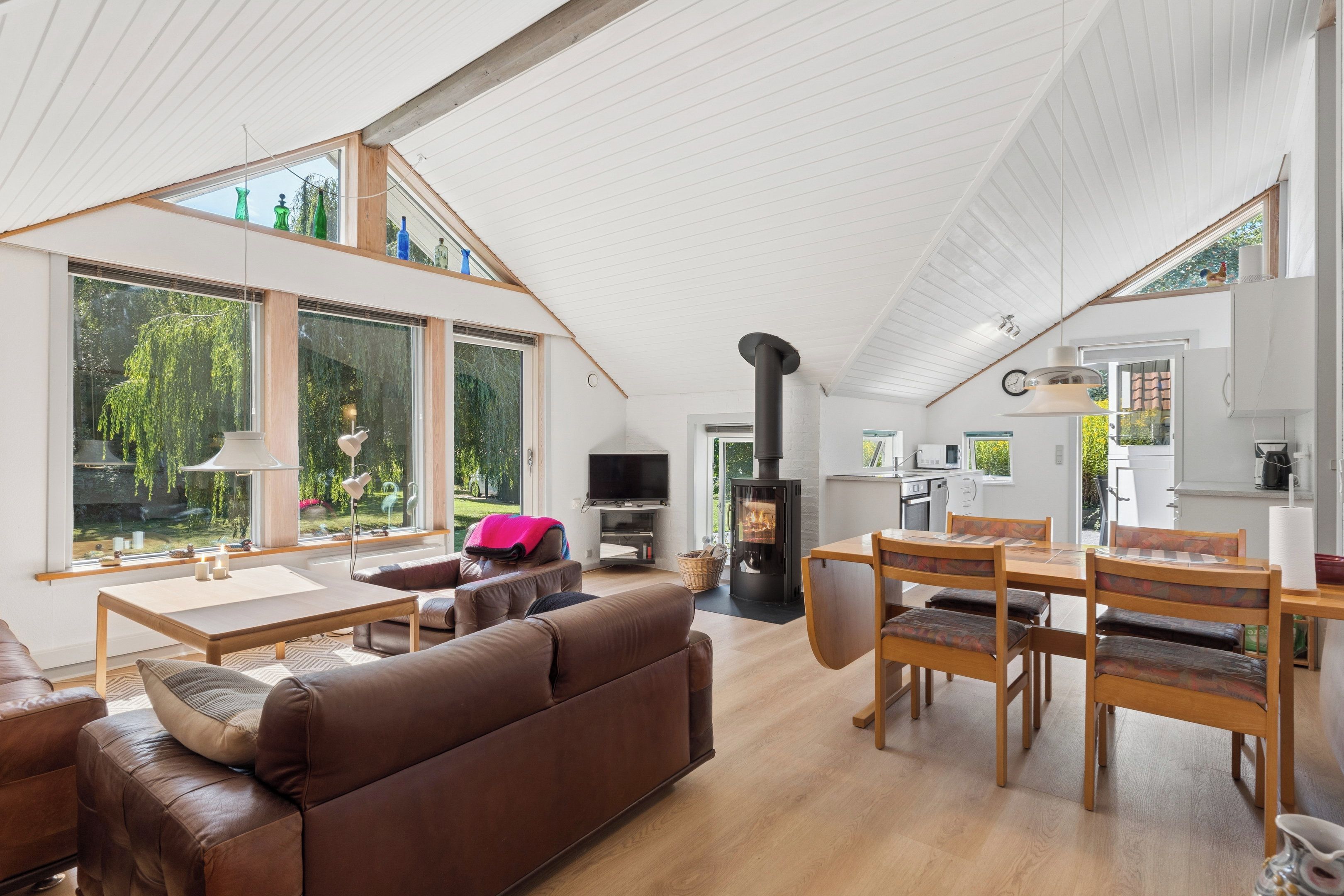 A spacious living area with a high ceiling, a fireplace, and a dining table with chairs.