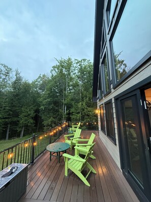 A deck with outdoor seating and a view of a forested area. - Shark Belly Mountain Chalet - the Ultimate Lux Mountain Retreat (Bethel)