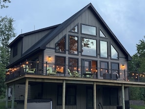 A two-story building with large windows and a balcony with string lights. - Shark Belly Mountain Chalet - the Ultimate Lux Mountain Retreat (Bethel)