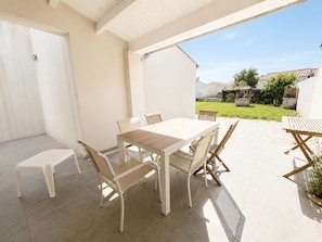 An outdoor patio with a table and chairs, a small stool, and a potted plant. - Lovely, fully equipped holiday home (LA COUARDE SUR MER)