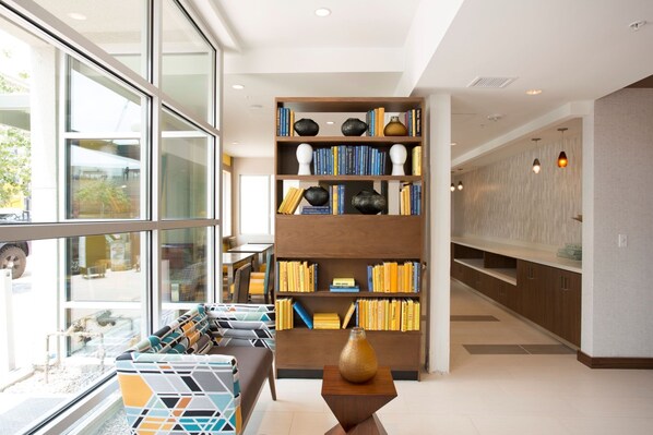 Ein modernes Interieur mit einer gro ßen Bücherwand, einer Sitzecke und Blick durch große Fenster.