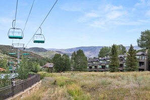 Una seggiovia con cabine, uno sfondo montuoso e moderni edifici residenziali.