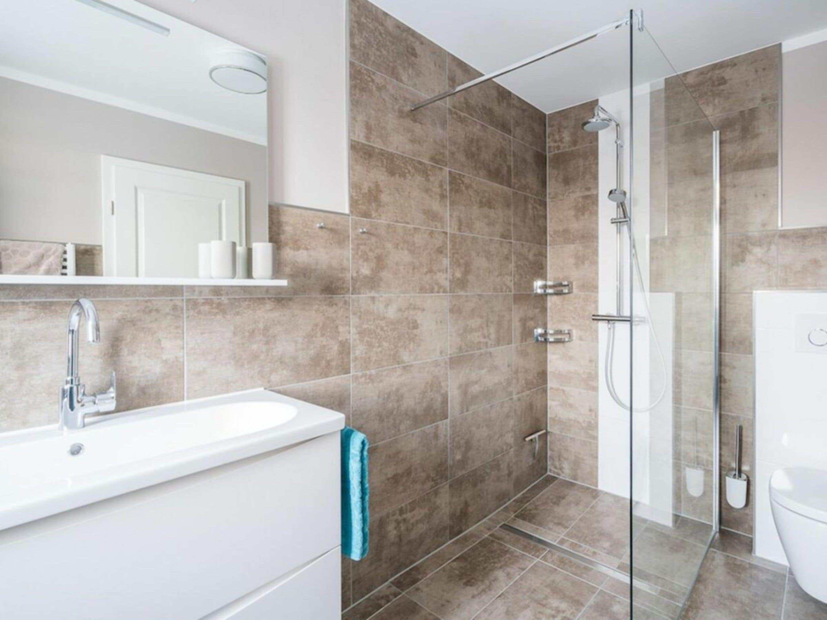 A modern bathroom with a glass shower enclosure, a white sink, and a toilet.