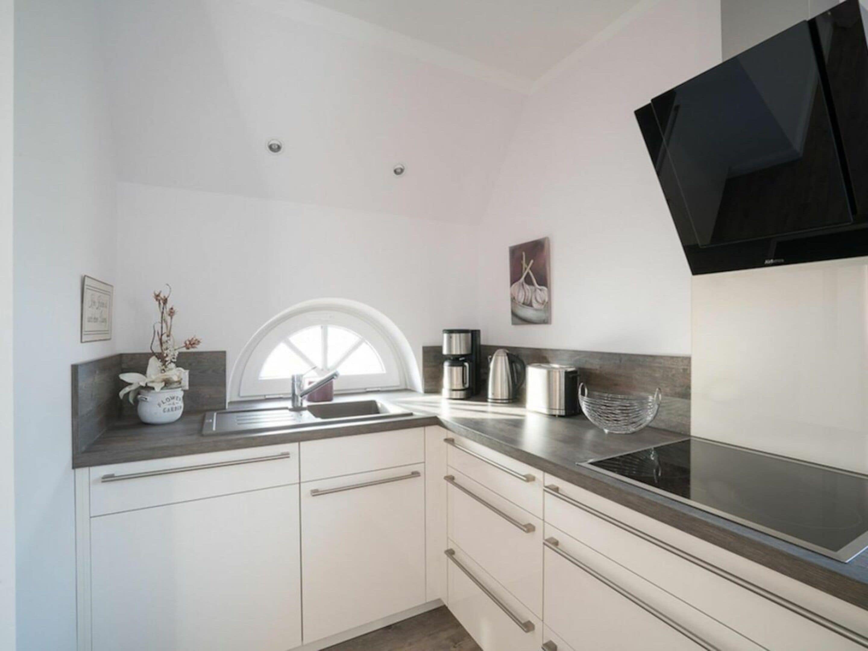A modern kitchen with white cabinets, a black countertop, and a built-in stove.