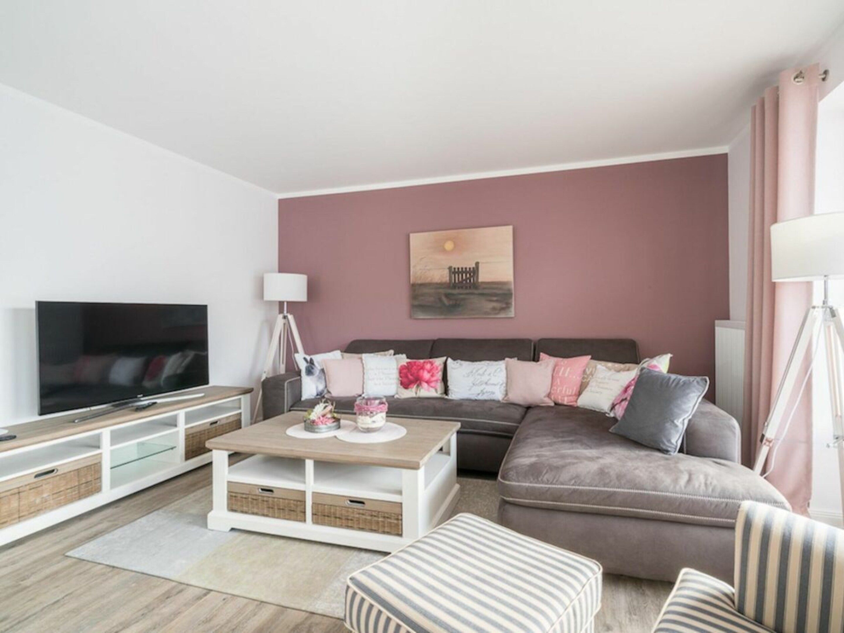 A modern living room with a flat-screen TV, a sofa, a coffee table, and a lamp.