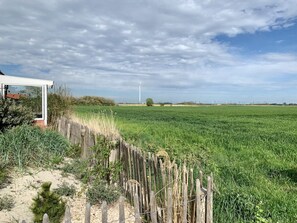 A rural landscape with a field, a wooden fence, and a wind turbine in the distance. - Mariechen am Meer Apt. 1 - Norddeich (Norden)