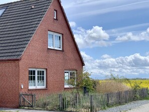 Ein rotes Backsteinhaus mit geneigtem Dach und zwei Fenstern.