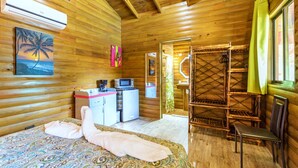 A wooden cabin room with a bed, a kitchenette, a shower area, and a window with curtains. - Tropical Paradise w/ 2 Sapacious Cabinas AC & Pool (Playa Herradura)
