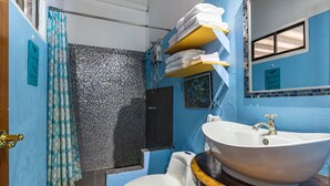 A bathroom with a shower, toilet, sink, and towels on a shelf. - Tropical Paradise w/ 2 Sapacious Cabinas AC & Pool (Playa Herradura)