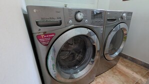 A front-loading LG Direct Drive 20.0kg washer and dryer unit in a laundry room with tiled flooring and a window above the machines.