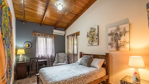A bedroom with a bed, a desk, a chair, a zebra-patterned rug, and artwork on the walls. - Stylish & Cozy Private Rooms in Tropical Paradise (Playa Herradura)