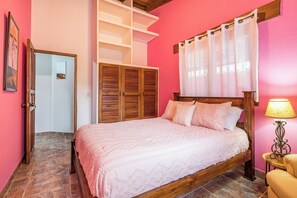 A bedroom with a wooden bed, a nightstand, a lamp, and a wardrobe.