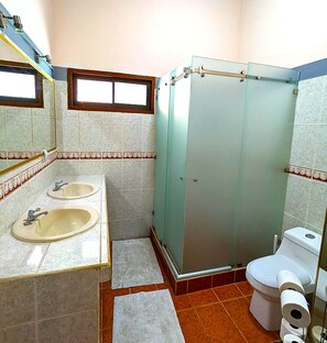 Een badkamer met twee wastafels, een toilet en een douchecabine van glas.