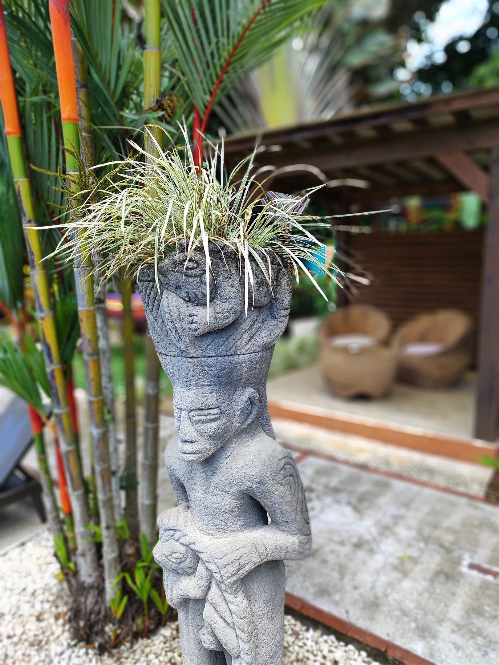 Une statue de pierre représentant un visage et des mains, tenant une plante.