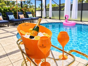 A poolside setting with a champagne bucket, glasses, and a flamingo float.