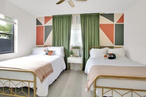 Une chambre avec deux lits, une table de chevet, une lampe et une fenêtre avec des rideaux.