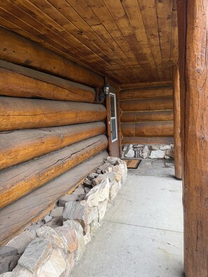 A log cabin interior with a stone foundation, wooden walls, and a door leading outside. - Chena Riverside Lodge (Fairbanks)