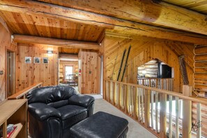 A log cabin interior with a leather sofa, a dining area, and a television. - Chena Riverside Lodge (Fairbanks)