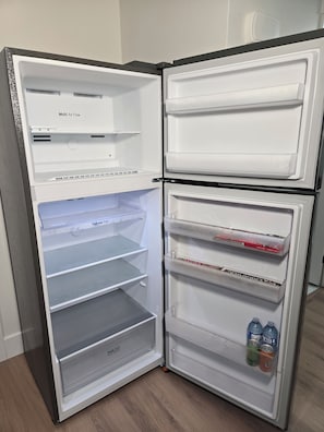 Ein Kühlschrank mit mehreren Ablagen, einer ausziehbaren Schiene und einer Frischezone.