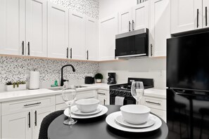 A modern kitchen with white cabinets, a black stove, and a black refrigerator. - Your Downtown Base | Walk to Petco Park & Gaslamp! (San Diego)