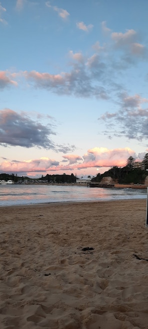 A beach with sand, a body of water, and a distant shoreline with buildings. - Family home walking distance to Terrigal beach (Terrigal)