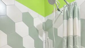 Chuveiro com padrão de azulejos hexagonais, um chuveiro e uma cortina.