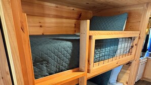 Una cama litera con estructura de madera y un estante inferior.