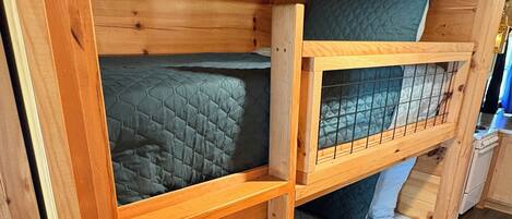 Un lit superposé avec une structure en bois et une étagère inférieure.