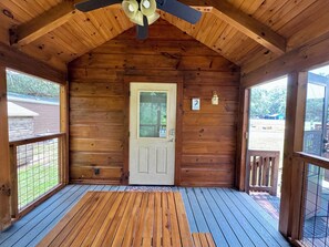 Eine Holzhütte mit Veranda, Deckenventilator und einer Tür mit Schild zum Haustierrichtlinien.
