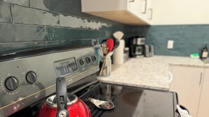 A kitchen with a stove, a red kettle, and a coffee maker. - Cozy Two-Storey Suite in Maple Bay (Duncan)