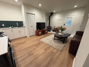 Ein modernes Wohnzimmer mit Fernseher, Holzboden, Couchtisch und braunem Ledersofa.