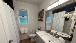 A bathroom with a toilet, sink, and mirror. - Cozy Two-Storey Suite in Maple Bay (Duncan)