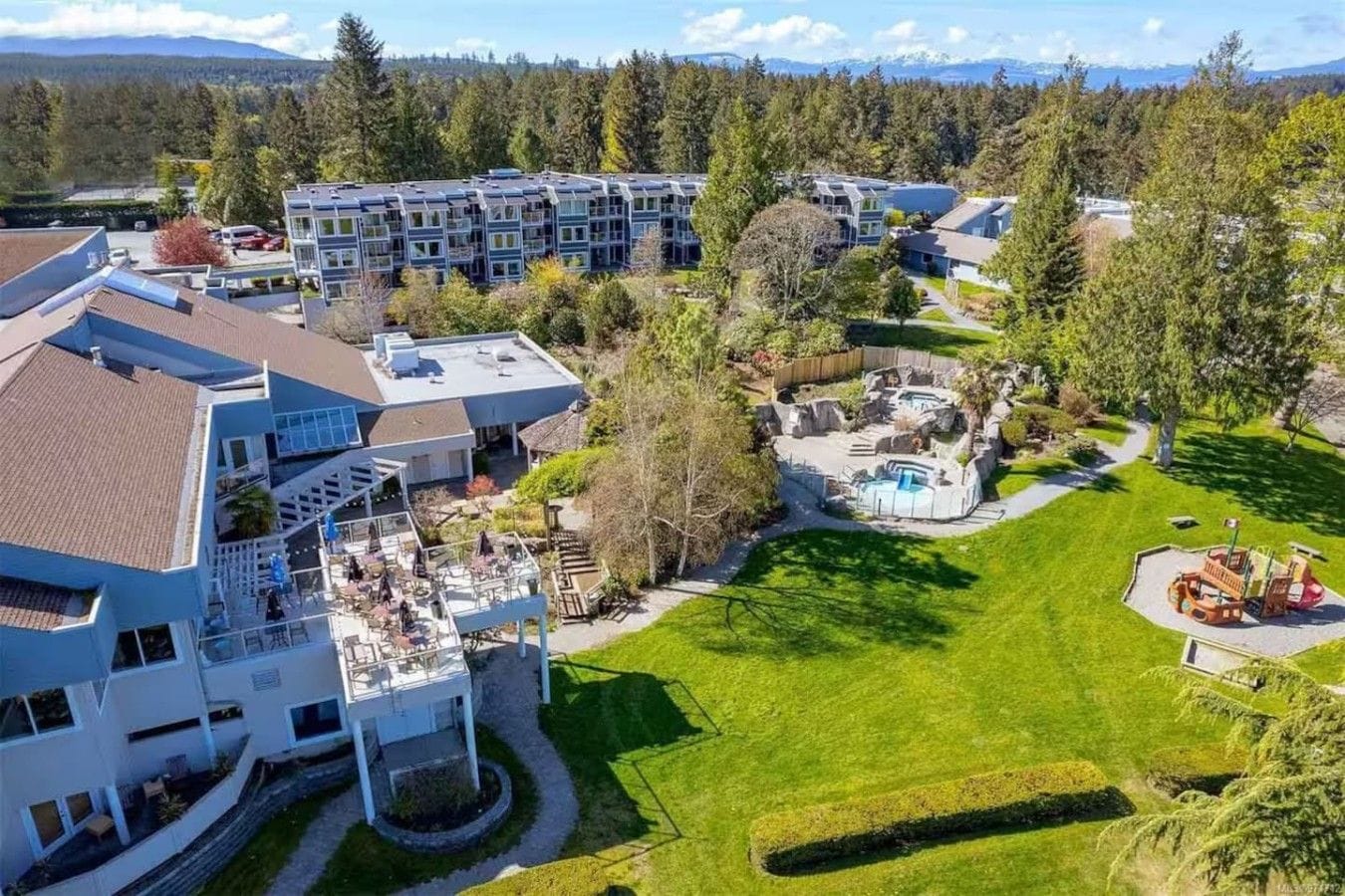 A residential complex with multiple buildings, a swimming pool, and a playground.