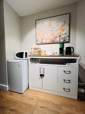 A kitchenette with a microwave, a small refrigerator, a coffee maker, and a cabinet with drawers. - Oceanside Garden Studio B: Pool & Hot tub (Nanoose Bay)