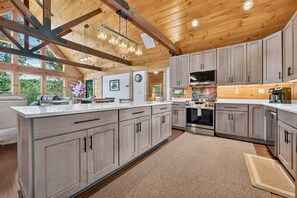 A spacious kitchen with wooden cabinets, a stainless steel oven, and a large island with a sink. - Blue Ridge Retreat on Wolf Creek - Hot Tub, Game Room, Firepit + EV Charger (Mineral Bluff)