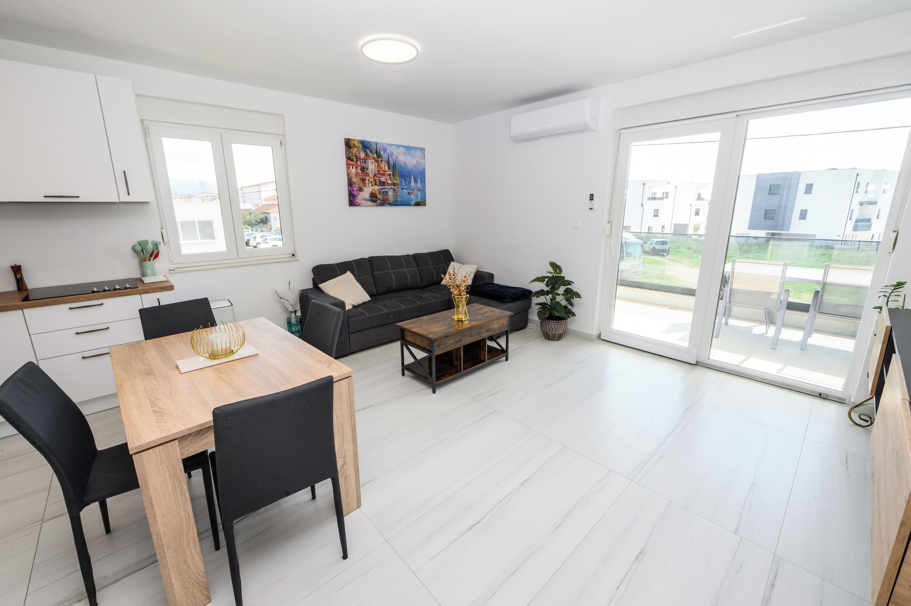 A modern living space with a dining area, sofa, and large sliding glass doors leading to an outdoor area.