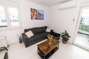 A modern living room with a sectional sofa, a wooden coffee table, and a potted plant. - Condo with 2 bdr and parking (Kaštel Stari)