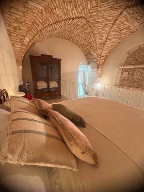 Ein Schlafzimmer mit einem großen Bett, einem Holzschrank und einer Steindecke.