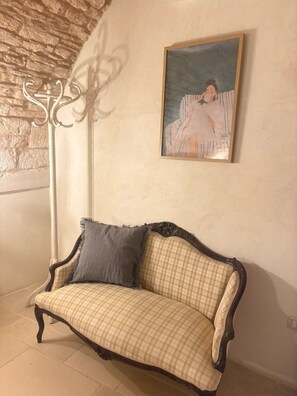 A room with a checkered sofa, a painting on the wall, and a decorative metal stand. - PalazzOliva - Historic Heart of Martina Franca (Martina Franca)