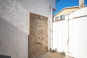 A door with a metal handle and a keyhole, a small statue, and a white gate. - Beachfront Studio Steps to Main Street (Seal Beach)