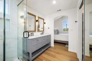 Et moderne badeværelse med et brusekabine i glas, et skab med dobbelt vask og et stort spejl.