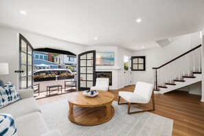 A spacious living room with a fireplace, a round wooden coffee table, and a white sofa. - Classic Balboa Island Coastal Escape (Newport Beach)